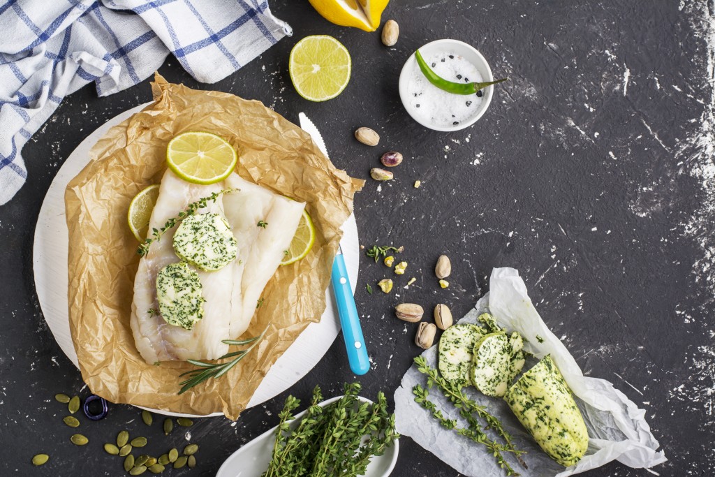 homemade green butter with herbs on a dark background with slices of lemon, thyme, sea salt