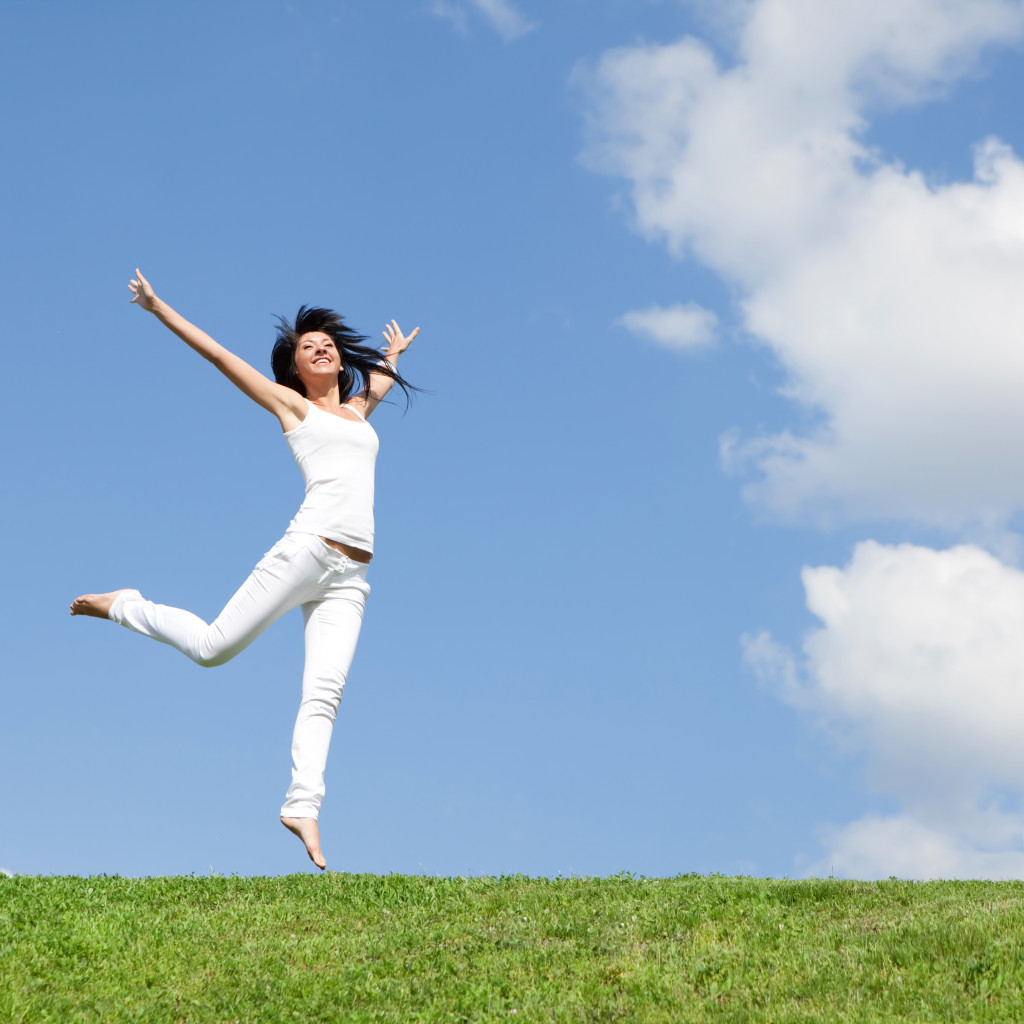 picture of a happy woman who jumped on a grassland