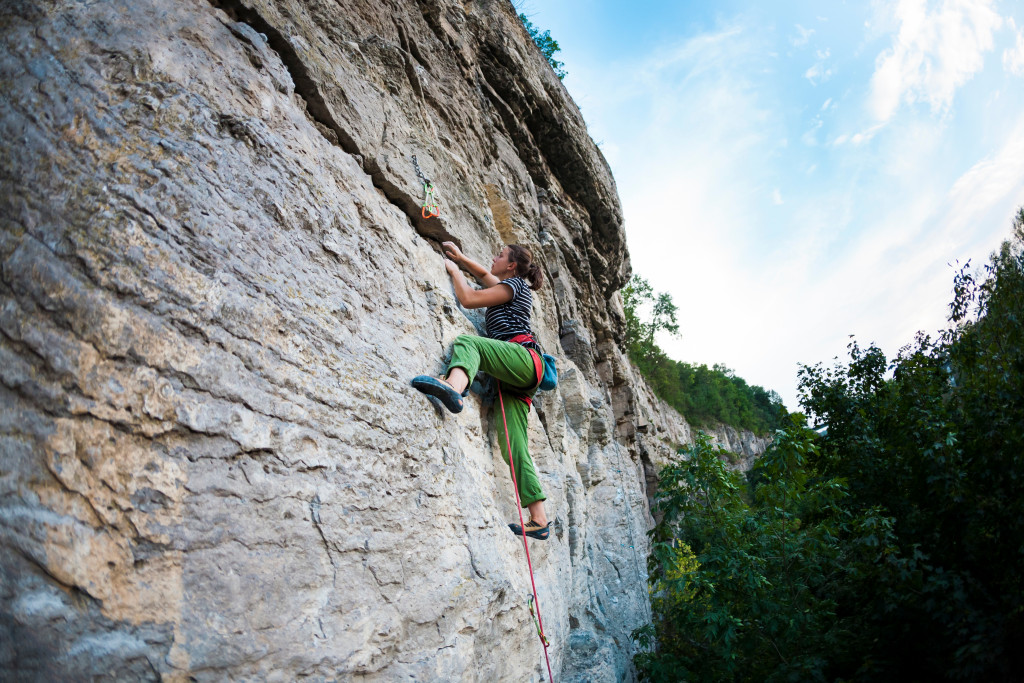 brave woman climbing rock wit harness