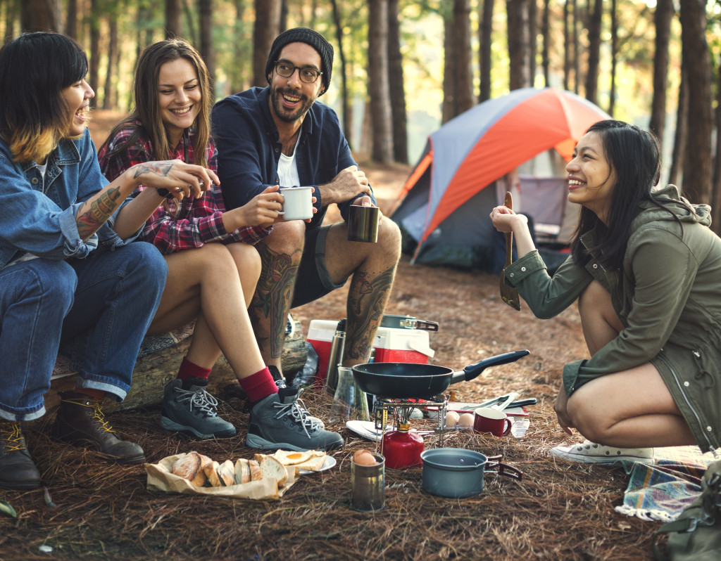 employees friends happily eating while camping in the woods